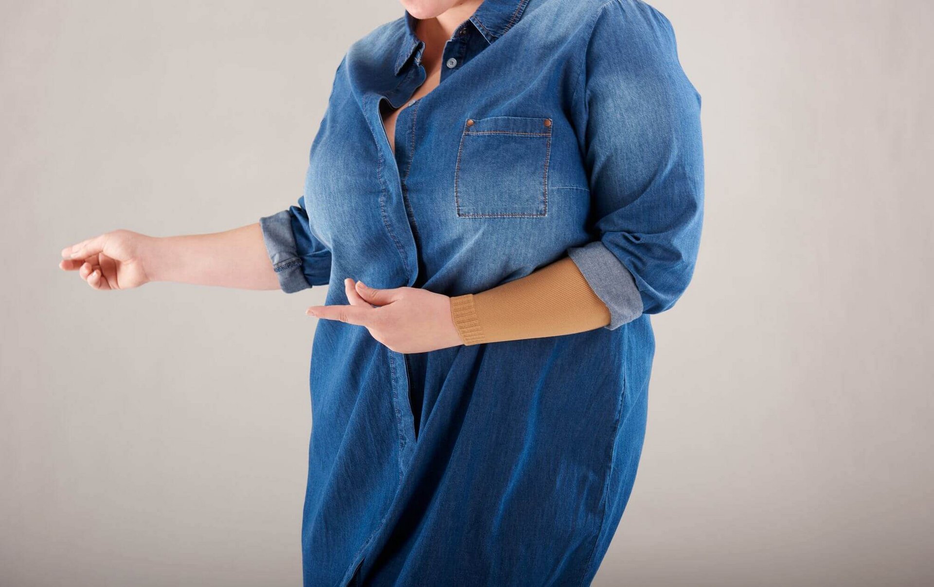 Bildausschnitt einer Frau mit Jeanshemd und curaflow-Flachstrick Kompression von Bauerfeind am linken Arm.